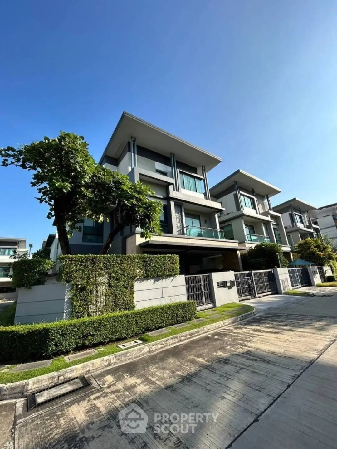 Modern luxury townhouse with lush greenery and sleek architecture in a serene neighborhood.