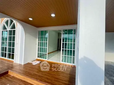 Elegant patio with wooden flooring and sliding glass doors leading to a bright interior space.