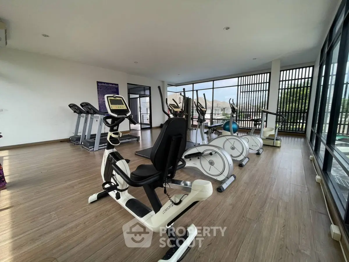 Modern gym with exercise equipment and large windows in a residential building
