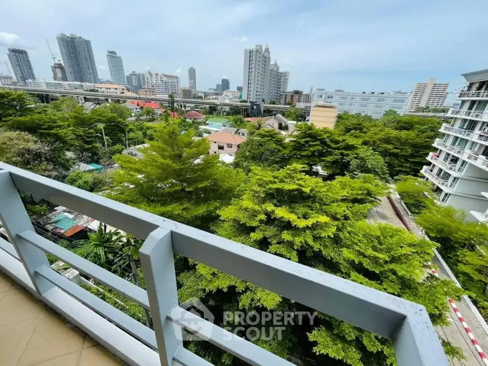 Stunning cityscape view from a high-rise balcony overlooking lush greenery and urban skyline.