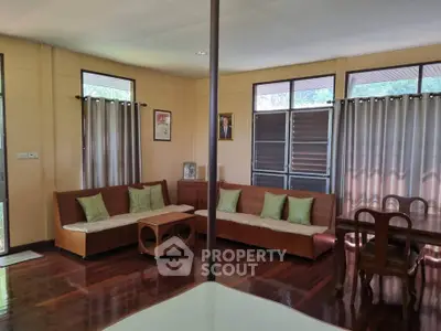 Charming living room with wooden floors, cozy seating, and natural light through large windows.