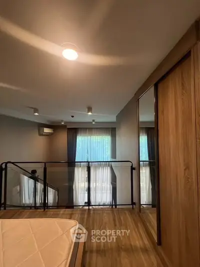 Modern bedroom with wooden flooring and large windows in a stylish apartment.