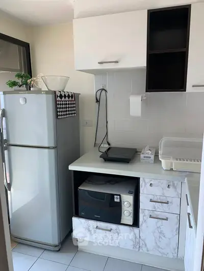 Modern kitchen with sleek appliances and ample storage space, featuring a fridge and microwave.