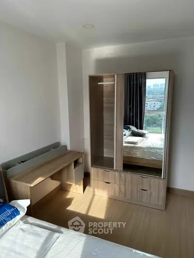 Bright bedroom with wooden furniture and city view from window