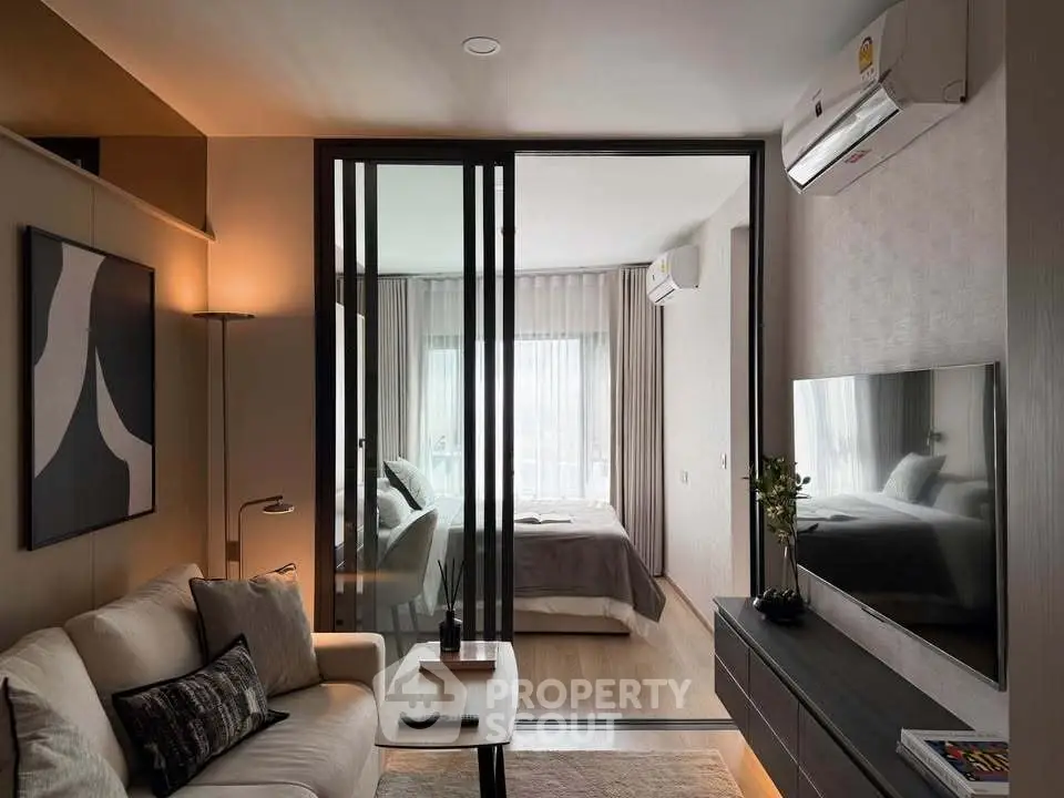 Modern living room with sliding doors leading to a cozy bedroom, featuring stylish decor and natural light.