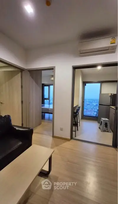 Modern apartment interior with open layout, featuring a cozy living area and kitchen with city view.