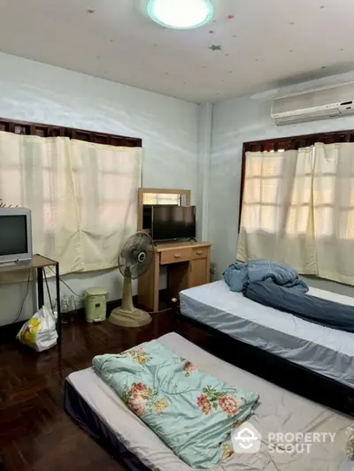 Cozy bedroom with twin beds, air conditioning, and natural light from large windows.