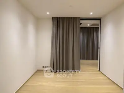 Spacious empty room with wooden flooring and elegant curtains, perfect for customization.