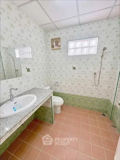 Spacious bathroom with floral tiles and modern fixtures in a real estate property.