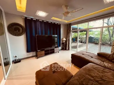 Spacious living room with large TV and garden view, perfect for relaxation.