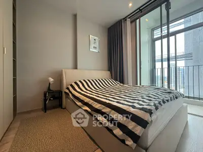 Modern bedroom with striped bedding and balcony view in urban apartment
