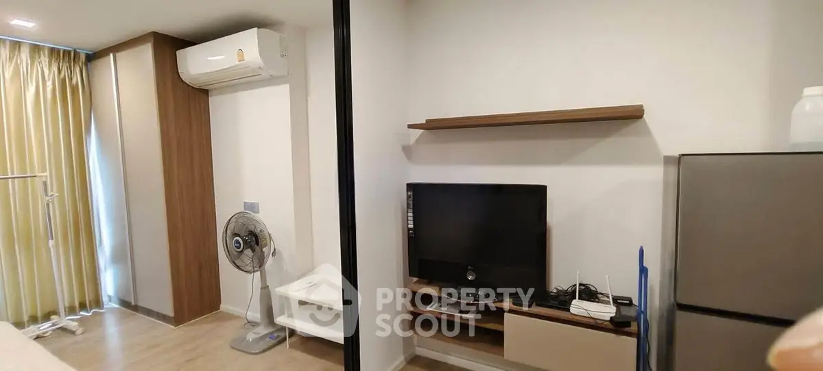 Modern apartment interior with air conditioning, TV, and fridge, showcasing compact living space.