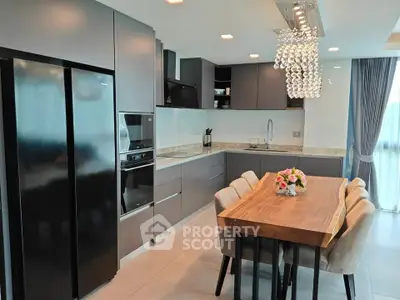 Modern kitchen with sleek cabinetry, dining table, and elegant chandelier