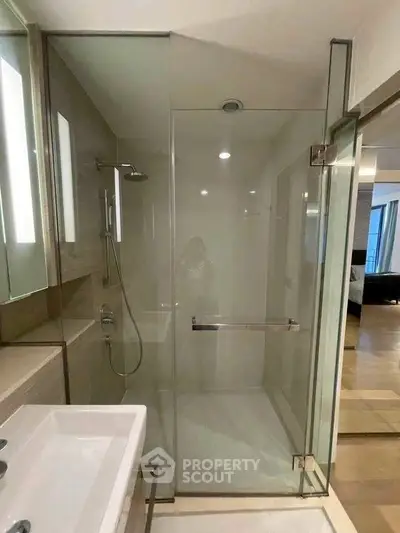 Modern bathroom with glass shower enclosure and sleek fixtures in a contemporary apartment.