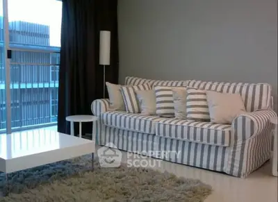 Modern living room with striped sofa and floor-to-ceiling window view.