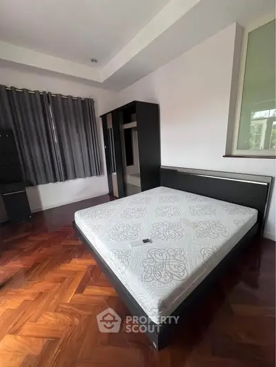 Spacious bedroom with elegant parquet flooring and modern furnishings