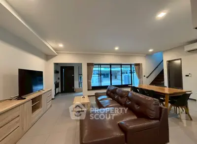 Spacious modern living room with leather sofa and large windows for natural light.