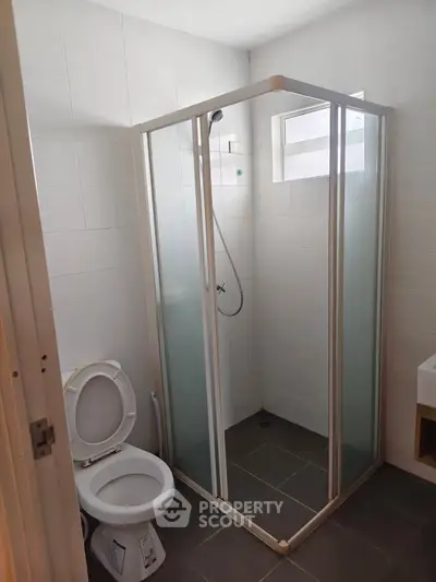 Modern bathroom with glass shower enclosure and sleek white tiles.