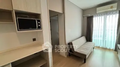 Modern living room with natural light, featuring a compact sofa and built-in microwave.