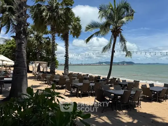 Stunning beachfront dining area with palm trees and ocean view, perfect for relaxation and leisure.