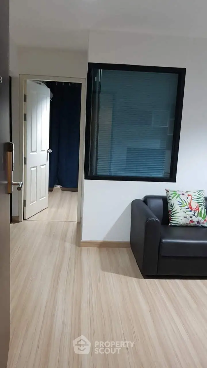Modern apartment interior with sleek black sofa and wooden flooring, showcasing a cozy and inviting living space.