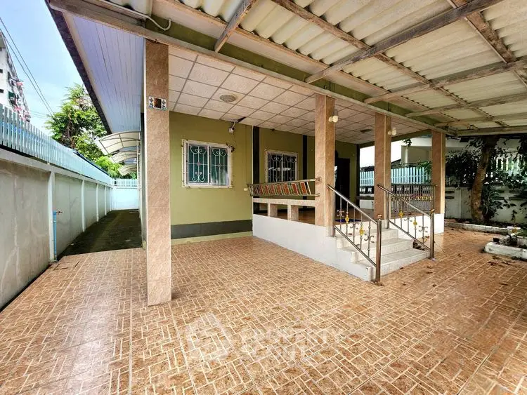 Spacious covered patio with tiled flooring and sturdy columns in a residential property.