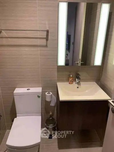 Modern bathroom with sleek fixtures and illuminated mirror in contemporary apartment.