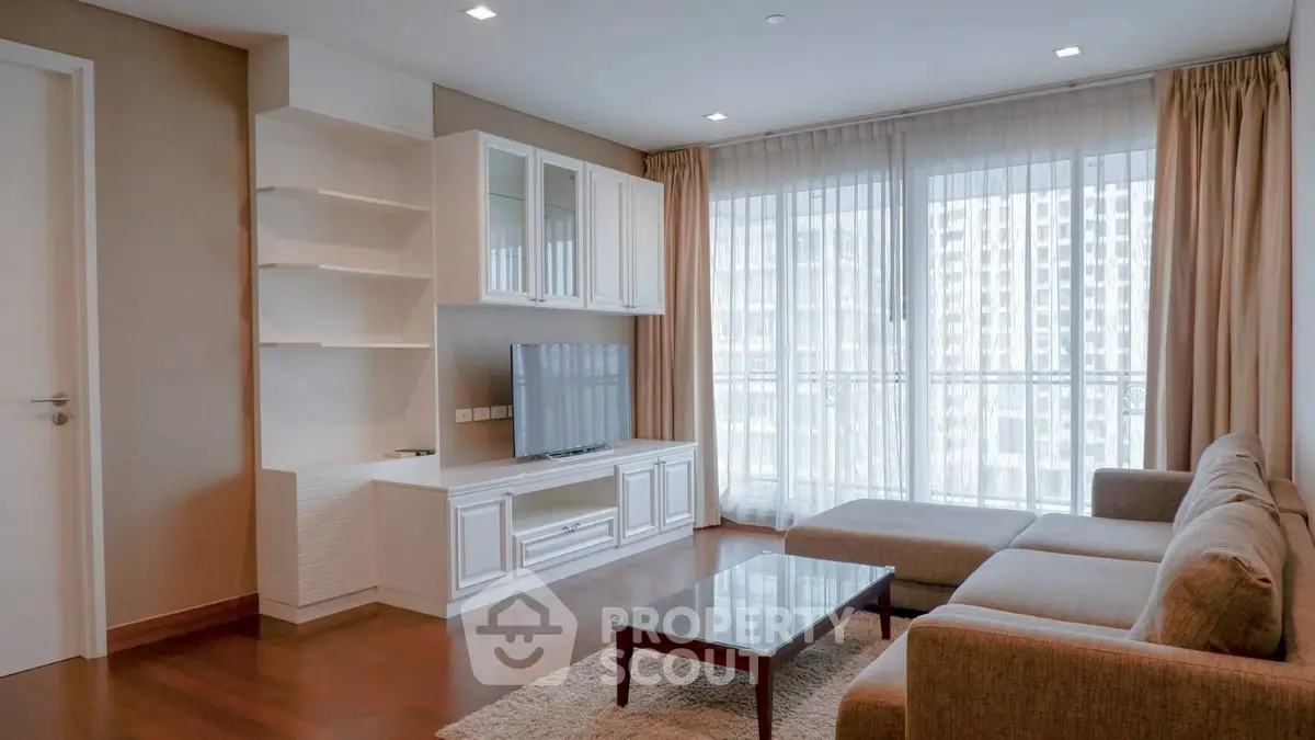 Spacious living room with modern furniture and large windows offering city views.