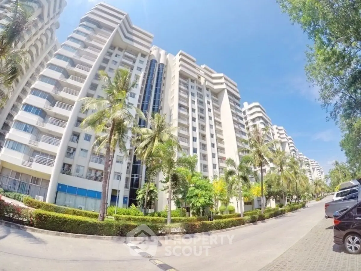 Luxurious high-rise residential building with palm-lined entrance and modern architecture.