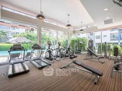 Modern gym with state-of-the-art equipment and large windows overlooking a pool area.
