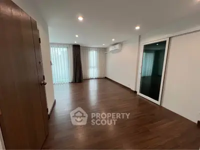 Spacious empty living room with wooden flooring and large windows