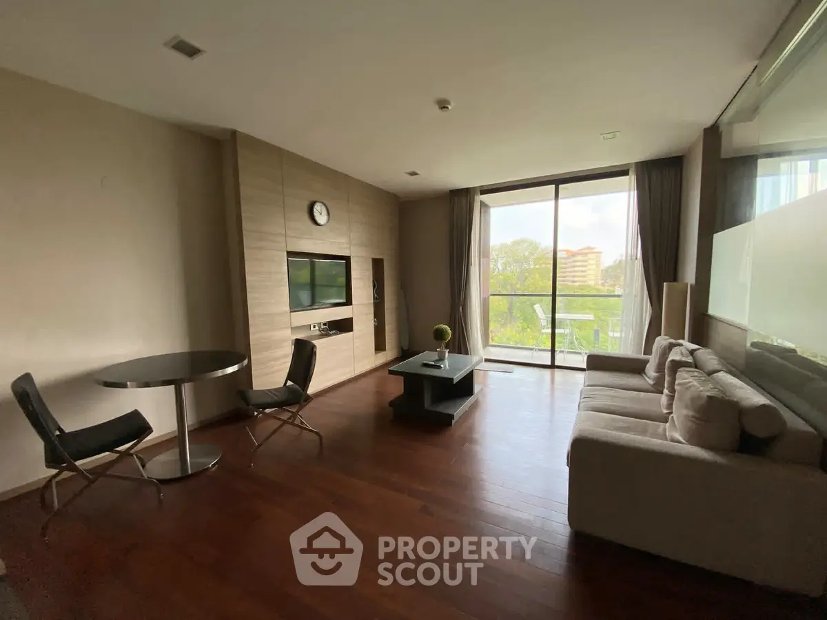 Spacious modern living room with wooden flooring and large windows offering a serene view.