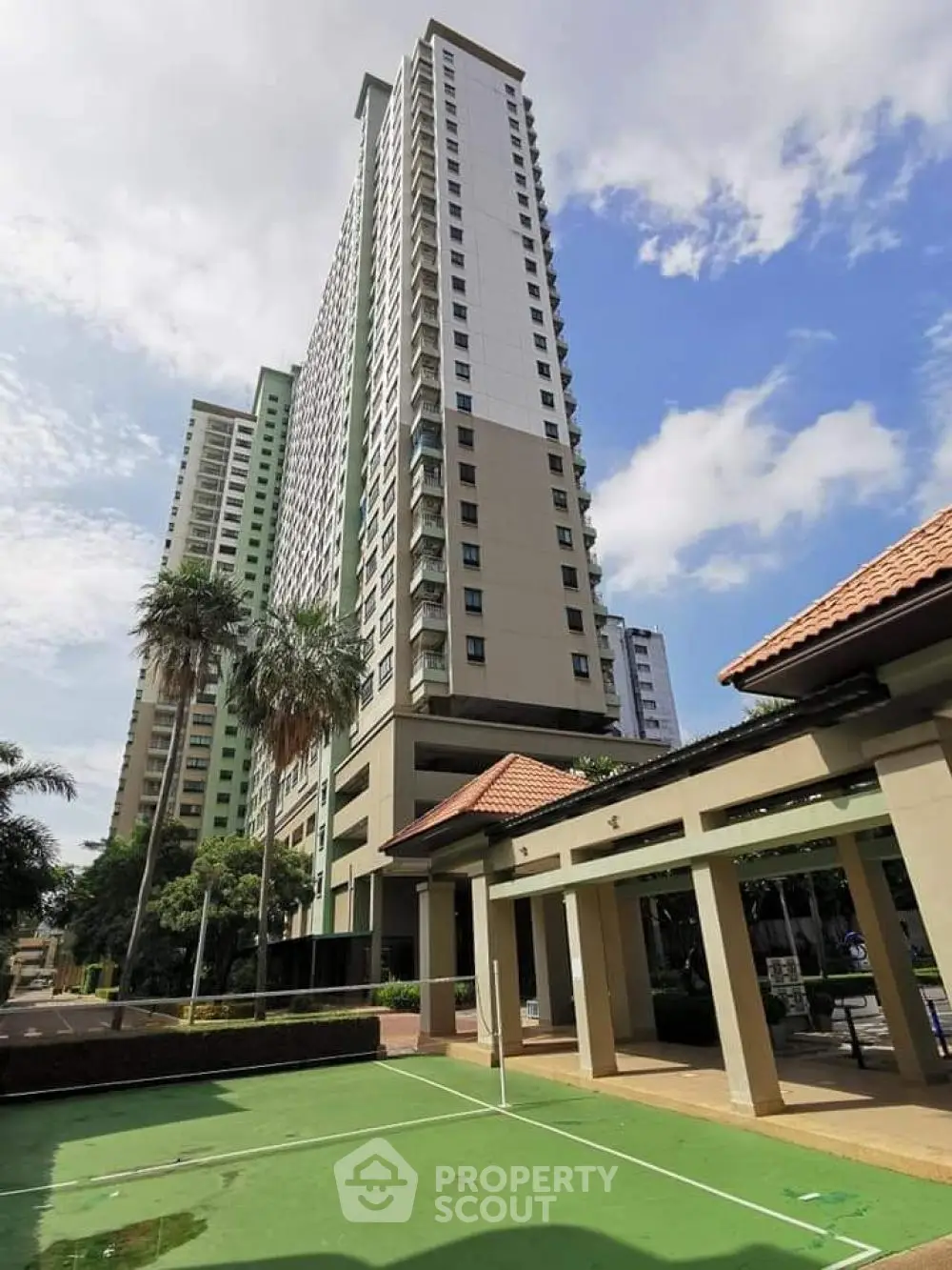 Stunning high-rise building with tennis court and lush greenery, perfect for urban living.