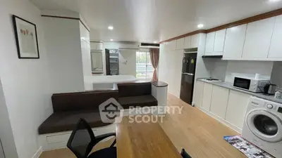 Modern open-plan living space with kitchen, dining, and laundry area, featuring sleek appliances and wooden flooring.