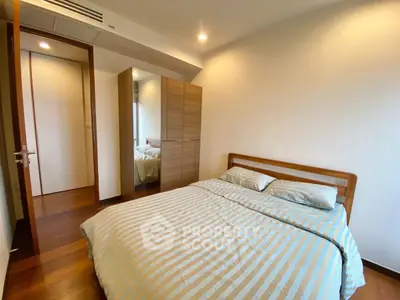 Cozy bedroom with wooden flooring and modern wardrobe in a stylish apartment.