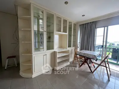 Spacious living area with built-in shelves and balcony view