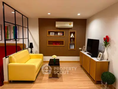 Modern living room with yellow sofa, TV, and stylish decor