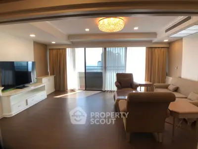 Spacious living room with elegant furniture and large windows leading to a balcony.