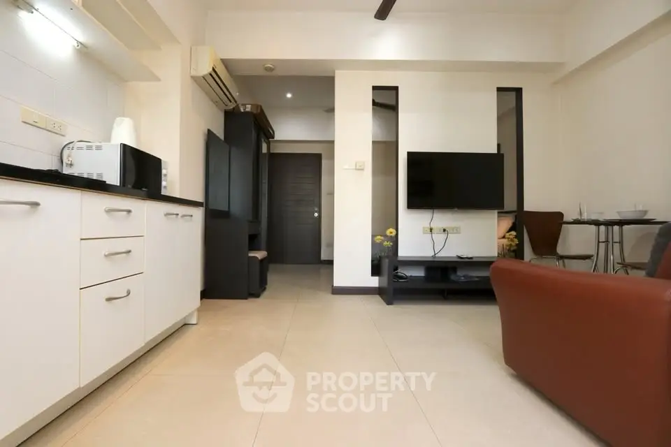 Modern living room with sleek furniture and open layout, featuring a wall-mounted TV and stylish decor.