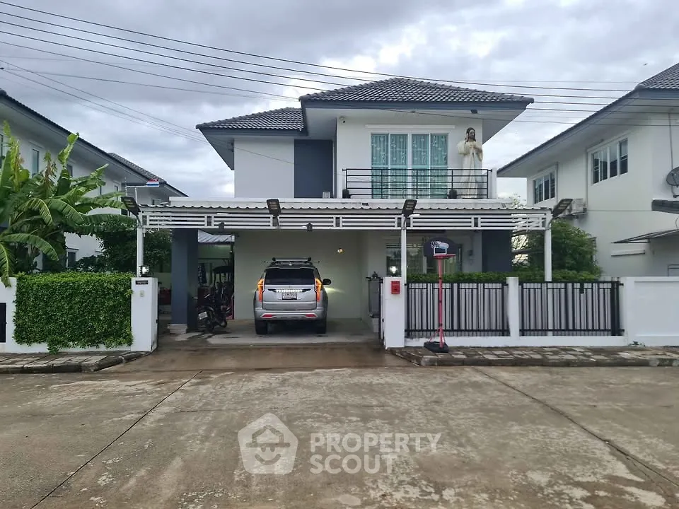 Modern two-story house with carport and gated driveway in a suburban neighborhood.