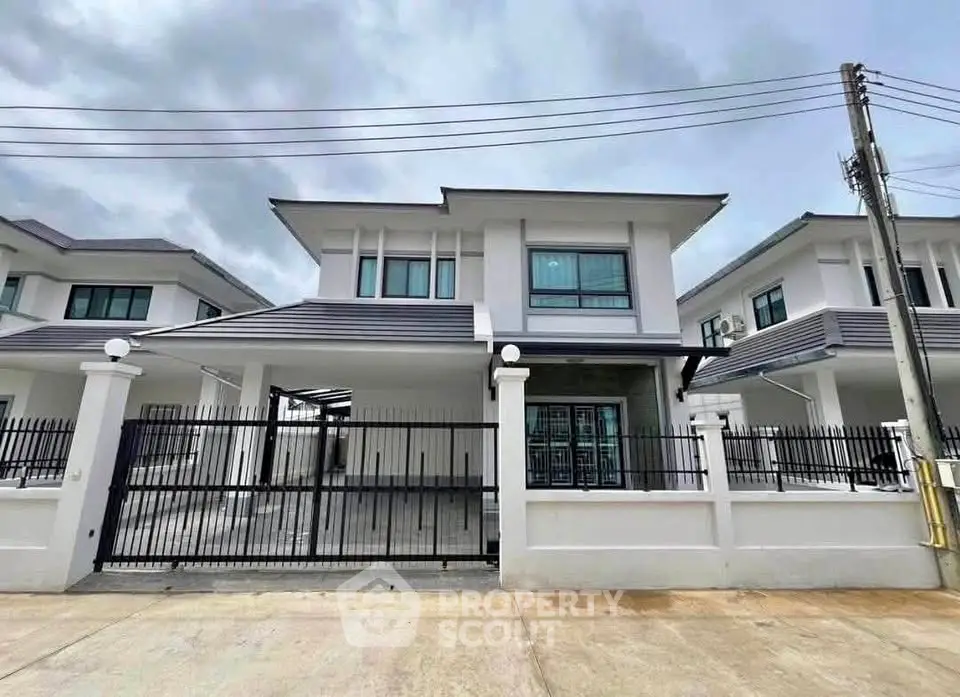 Modern two-story house with sleek design and gated entrance in suburban neighborhood.