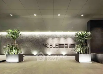 Modern building entrance with stylish lighting and potted plants, showcasing luxury and elegance.