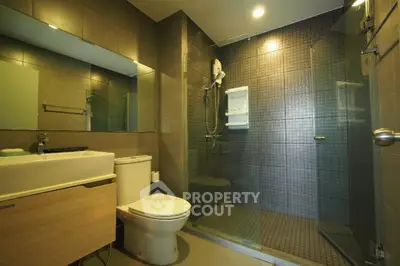 Modern bathroom with glass shower and sleek fixtures in contemporary home.