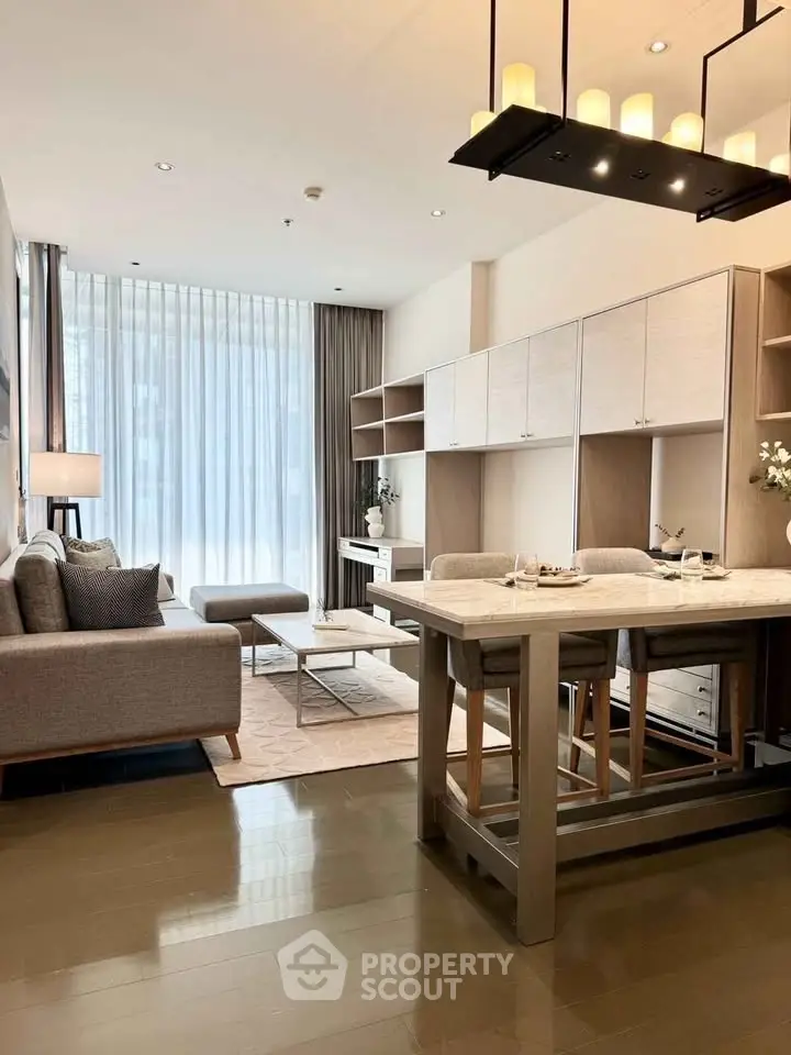Modern living room with open kitchen, elegant decor, and ample natural light.