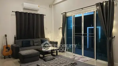 Cozy living room with modern decor, large sofa, and sliding glass doors leading to a patio.