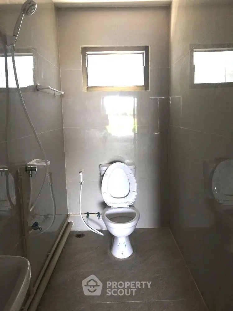 Modern bathroom with sleek fixtures and natural light from small windows.
