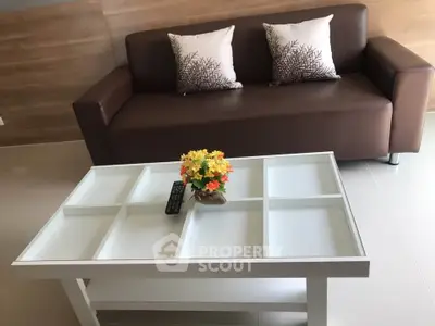 Modern living room with stylish brown sofa and white coffee table, accented by decorative pillows and flowers.