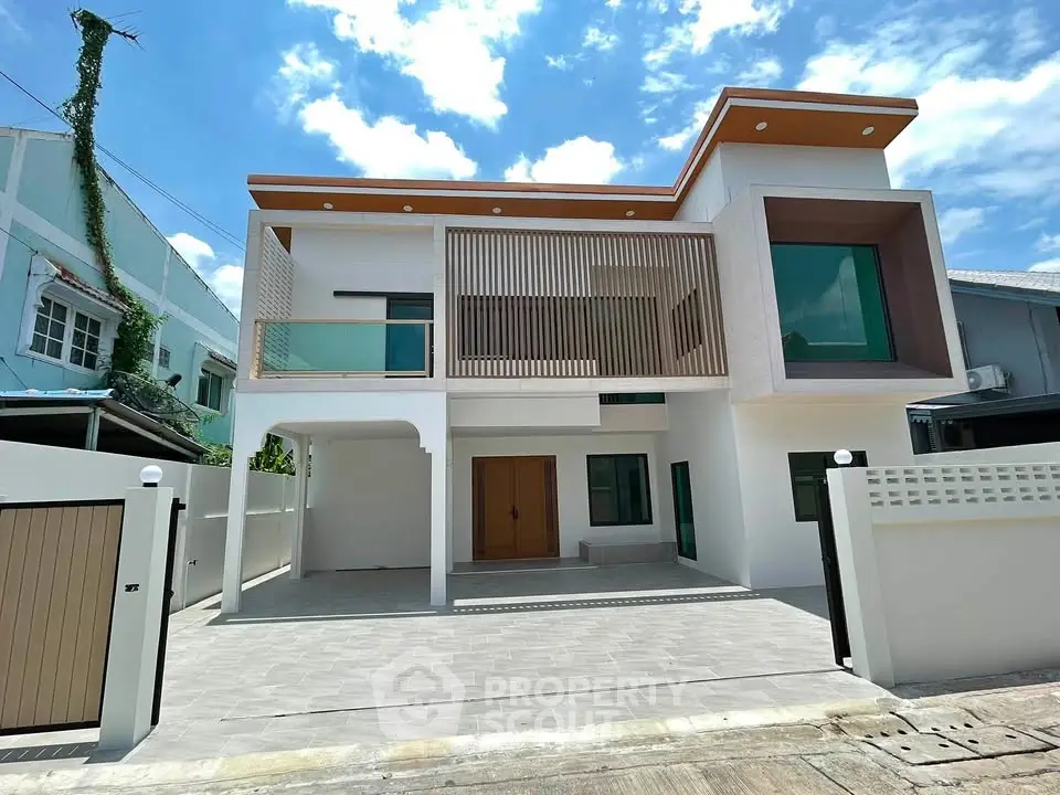 Modern two-story house with sleek design and spacious driveway under a clear blue sky.