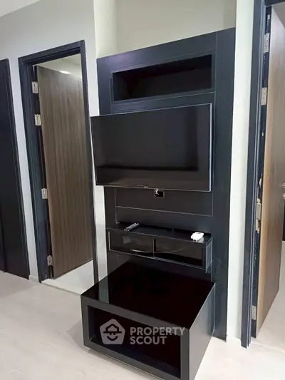 Modern living room with sleek TV unit and open doorways, showcasing contemporary interior design.