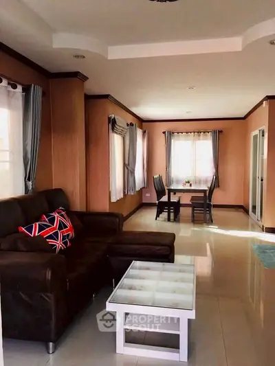 Spacious living room with modern decor and dining area, featuring large windows and stylish furniture.